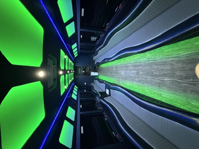 The Titan party bus interior with green LED ceiling panels and wrap-around seating