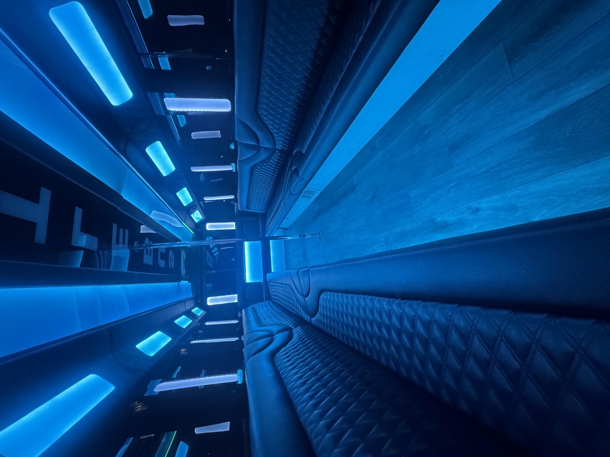 The Legacy party bus interior with blue LED lighting and extended diamond-stitched seating