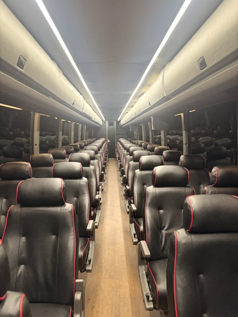 54-Person Motor Coach interior with black leather seats and red piping under LED lighting